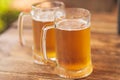 Two beer mugs closeup on wooden natural table.Two glass beer on wood background Royalty Free Stock Photo