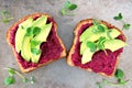 Two beet hummus and avocado toasts on a gray background