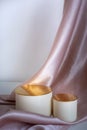 two beige cylinder catwalks with gold tops of different heights on a pink satin background with pleats. Royalty Free Stock Photo