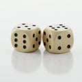 Two beige dice with black pips on a reflective white surface. Each die shows different Royalty Free Stock Photo