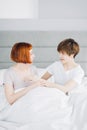 Two best female friends talking while resting on the bed indoors