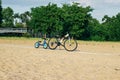 Two bicycles for children and adult stand on the parked beach