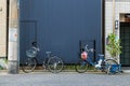 Two bicycles park in front of steel wall