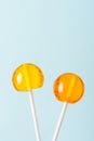 Two big bright tasty lollipops on white sticks blue pastel background Royalty Free Stock Photo