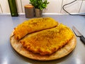 Two big calzone pizzas on wooden plate on big table Royalty Free Stock Photo