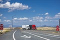 Two big rigs semi trucks with semi trailers transporting cargo driving side by side on the highway road with fork intersection in Royalty Free Stock Photo