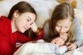 Two big sisters admiring their sleeping newborn brother. Two young girls holding their new baby boy. Kids with large age gap. Big Royalty Free Stock Photo