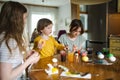 Two big sisters and their little brother dyeing Easter eggs at home. Children painting colorful eggs for Easter hunt. Kids getting Royalty Free Stock Photo