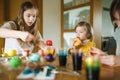 Two big sisters and their little brother dyeing Easter eggs at home. Children painting colorful eggs for Easter hunt. Kids getting Royalty Free Stock Photo