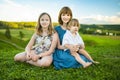 Two big sisters and their toddler brother having fun outdoors. Two young girls holding baby boy on summer day. Children with large Royalty Free Stock Photo