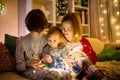 Two big sisters and their toddler brother playing with Chistmas lights in a cozy living room on Christmas eve. Kids spending time Royalty Free Stock Photo