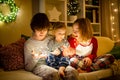 Two big sisters and their toddler brother playing with Chistmas lights in a cozy living room on Christmas eve. Kids spending time Royalty Free Stock Photo