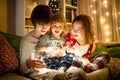 Two big sisters and their toddler brother playing with Christmas lights in a cozy living room on Christmas eve. Kids spending time Royalty Free Stock Photo