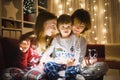 Two big sisters and their toddler brother playing with Christmas lights in a cozy living room on Christmas eve. Kids spending time Royalty Free Stock Photo