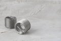 Two big wire thread inserts, grey color, free running on grey cement background. Stainless Steel. Horizontal with copy space for Royalty Free Stock Photo