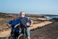 Two bikers with e bike stop to rest after a long excursion on the footpath along the atlantic ocean. Couple of senior people man