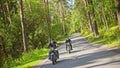 Two bikers are riding by each other along the road in the beatiful forest