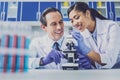 Two bioengineers wearing blue gloves using microscope Royalty Free Stock Photo