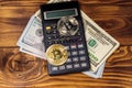 Two bitcoins, calculator and one hundred dollar bills on wooden desk Royalty Free Stock Photo