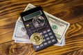 Two bitcoins, calculator and one hundred dollar bills on wooden desk Royalty Free Stock Photo