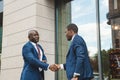 Two black african american businessmen in suits and glasses shake hands while meeting outdoors Royalty Free Stock Photo