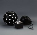 Two black balloons one of them with white polka dots on it and a black box with an open lid.