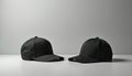 Two black baseball caps sit on clean light grey studio background. Present different angles of blank headwear. Use as mockup Royalty Free Stock Photo