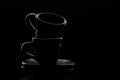 Two black ceramic coffee cups on saucers on a black background. Low key photography. Foreground. Royalty Free Stock Photo