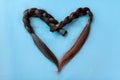 Two black chopped-off braids of human hair in a heart shape