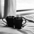 Two Black Coffee Cups On White Bed In Hotel Bedroom Royalty Free Stock Photo