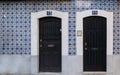 Two black doors in front of rustic old house with blue azulejo tiles walls. Typical Portuguese tile patterns, Lisbon