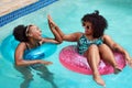 Two Black friends give high five, floating in pool inflatables, summer vacation Royalty Free Stock Photo