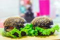 Two black hamburgers on a wooden Board close-up with salad, cheese, selective focus Royalty Free Stock Photo