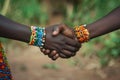 Two black hands clasping in unity, adorned with colorful bead bracelets