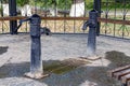 Two black iron water pump taps stand on a gray sidewalk in an open gazebo