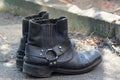 Two black leather old boots stand on gray asphalt Royalty Free Stock Photo