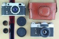 Two black old-school vintage photo cameras, brown leather case holder, films and lids. Flat lay, top view Royalty Free Stock Photo