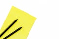 Two black pencil and a yellow Notepad on a white background. Minimal concept workplace at the office. Royalty Free Stock Photo