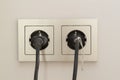 two black plugs are plugged into a double electrical outlet with a frame
