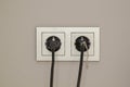 two black plugs are plugged into double electrical outlet with frame