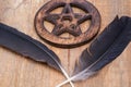Two Black Raven feathers and Wooden encircled Pentagram symbol on wood. Five elements: Earth, Water, Air, Fire, Spirit. Royalty Free Stock Photo