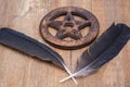 Two Black Raven feathers and Wooden encircled Pentagram symbol on wood. Five elements: Earth, Water, Air, Fire, Spirit. Royalty Free Stock Photo