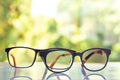 Two black shortsighted or nearsighted eyeglasses on white acrylic table, Bokeh green garden background, Reflection, Optical