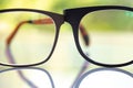 Two black shortsighted or nearsighted eyeglasses on white acrylic table, Bokeh green garden background, Reflection, Optical