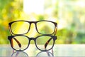 Two black shortsighted or nearsighted eyeglasses on white acrylic table, Bokeh green garden background, Reflection, Optical