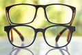 Two black shortsighted or nearsighted eyeglasses on white acrylic table, Bokeh green garden background, Reflection, Optical