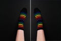 Two black socks with striped colorful pattern on black background with white line in center. Flat lay Royalty Free Stock Photo