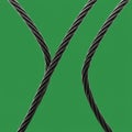 Two black, twisted cables cross against a solid green background. The cables are ma Royalty Free Stock Photo