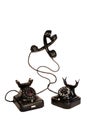 Two black vintage telephones entangled