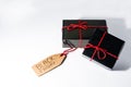 Two black wrapped gift boxes with a red cord and a Black Friday sales tag on a cardboard Royalty Free Stock Photo